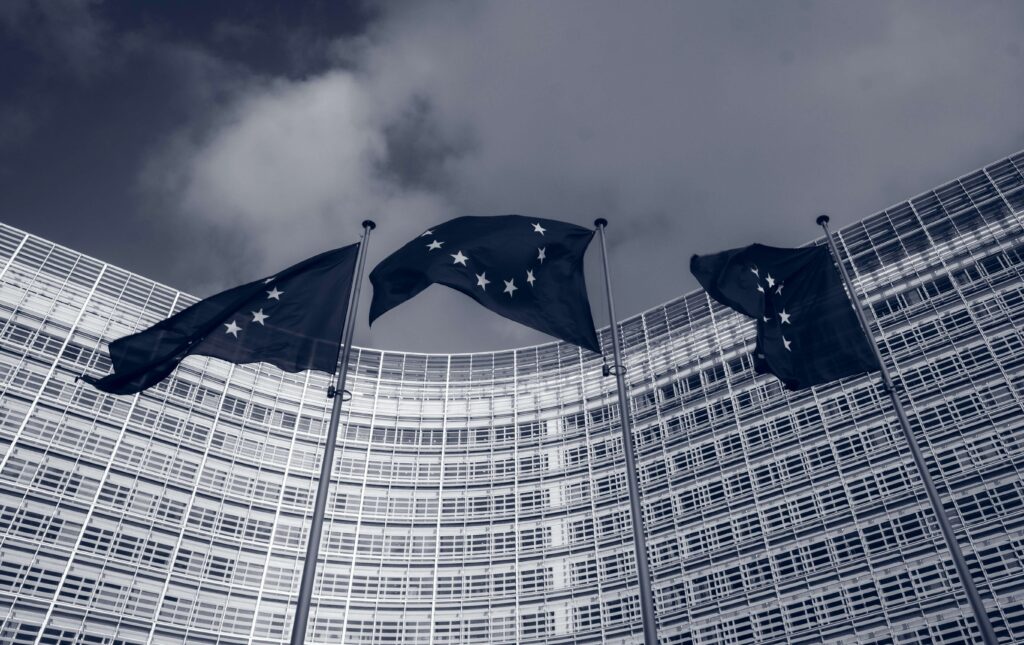 Palazzo di un istituzione europea con tre bandiere dell'Unione Europea che sventolano